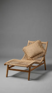 Woven lounge chair with a pillow on a gray background