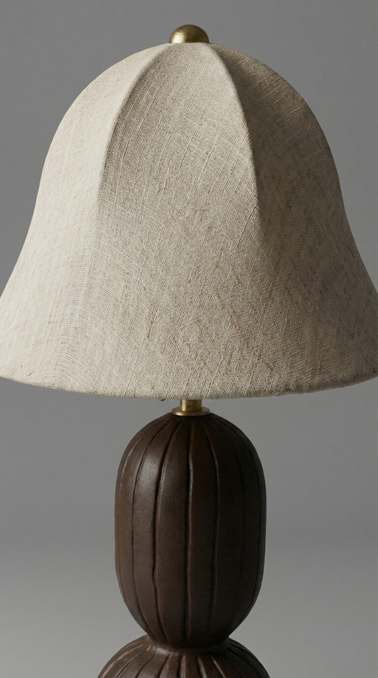 Table lamp with a beige fabric shade and brown base on a gray background