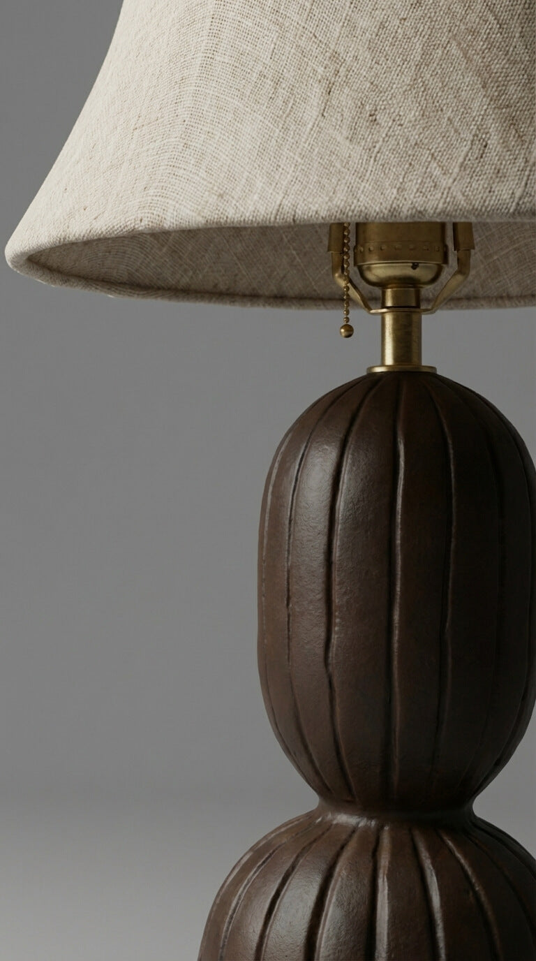 Close-up of a lamp with a brown base and beige lampshade on a gray background