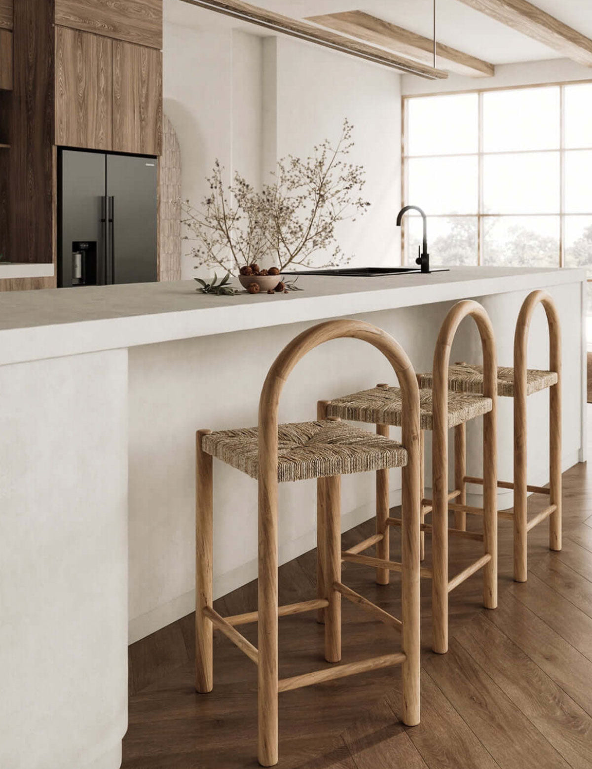 Three woven bar stools in a modern kitchen with white countertops and wooden flooring.