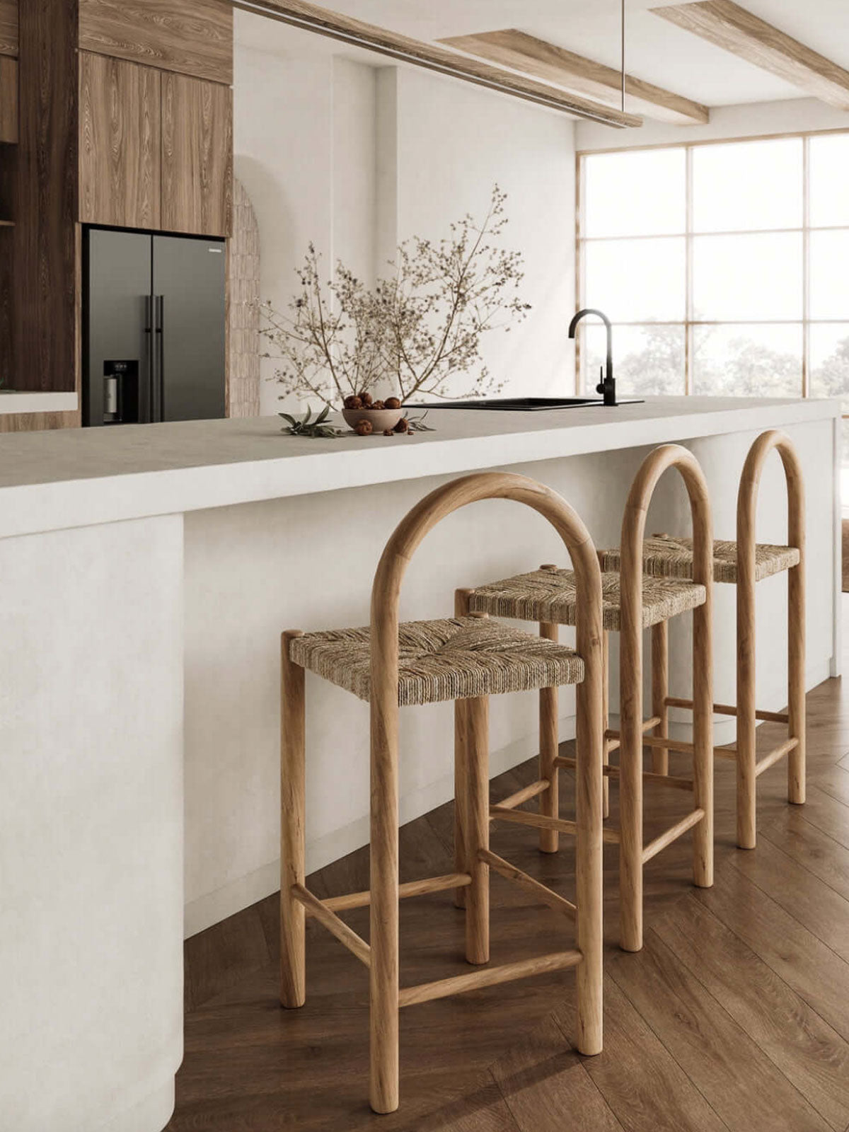 Three woven bar stools in a modern kitchen with white countertops and wooden flooring.
