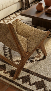 Woven chair on a patterned rug with a wooden coffee table in the background