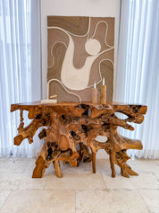 Wooden console table with natural root design in a room with abstract wall art.