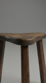 Wooden stool with a worn surface on a plain background