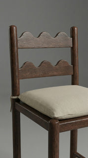Wooden chair with a beige cushion on a gray background
