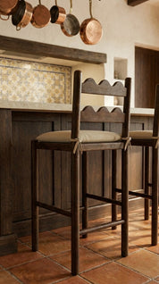 Wooden bar stools with cushioned seats in a rustic kitchen setting.