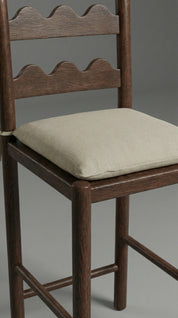 Wooden chair with a beige cushion on a gray background
