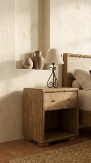 Wooden nightstand with lamp and decorative items in a bedroom setting