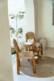 Wicker chairs and small round table in a bright room with plants and decor.
