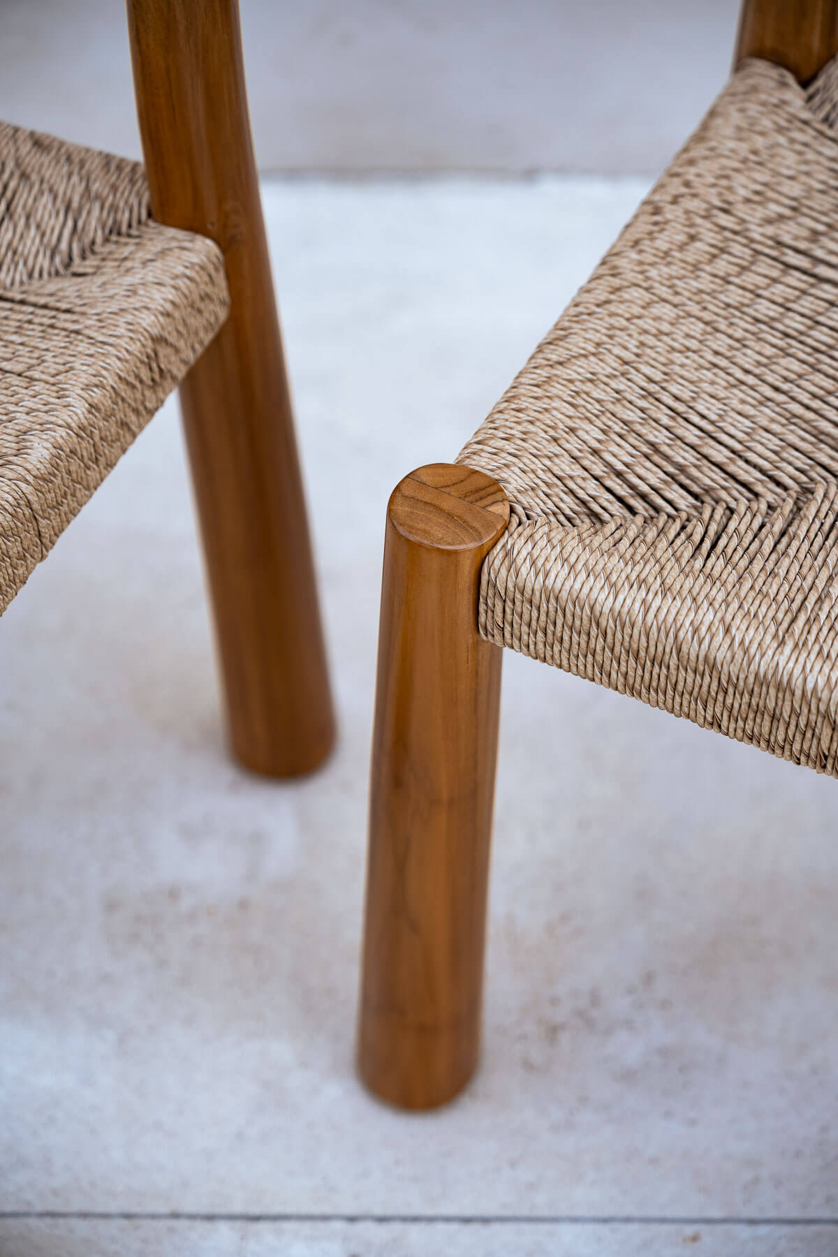 Close-up of wooden chair legs and woven seats on a light-colored floor.