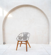 Wicker chair with wooden legs against a white wall with an arch