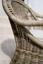 Handcrafted Tyo rattan armchair with curved armrests and woven headrest in natural autumn tones