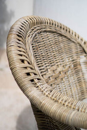 Handcrafted Tyo rattan armchair with curved armrests and woven headrest in natural autumn tones