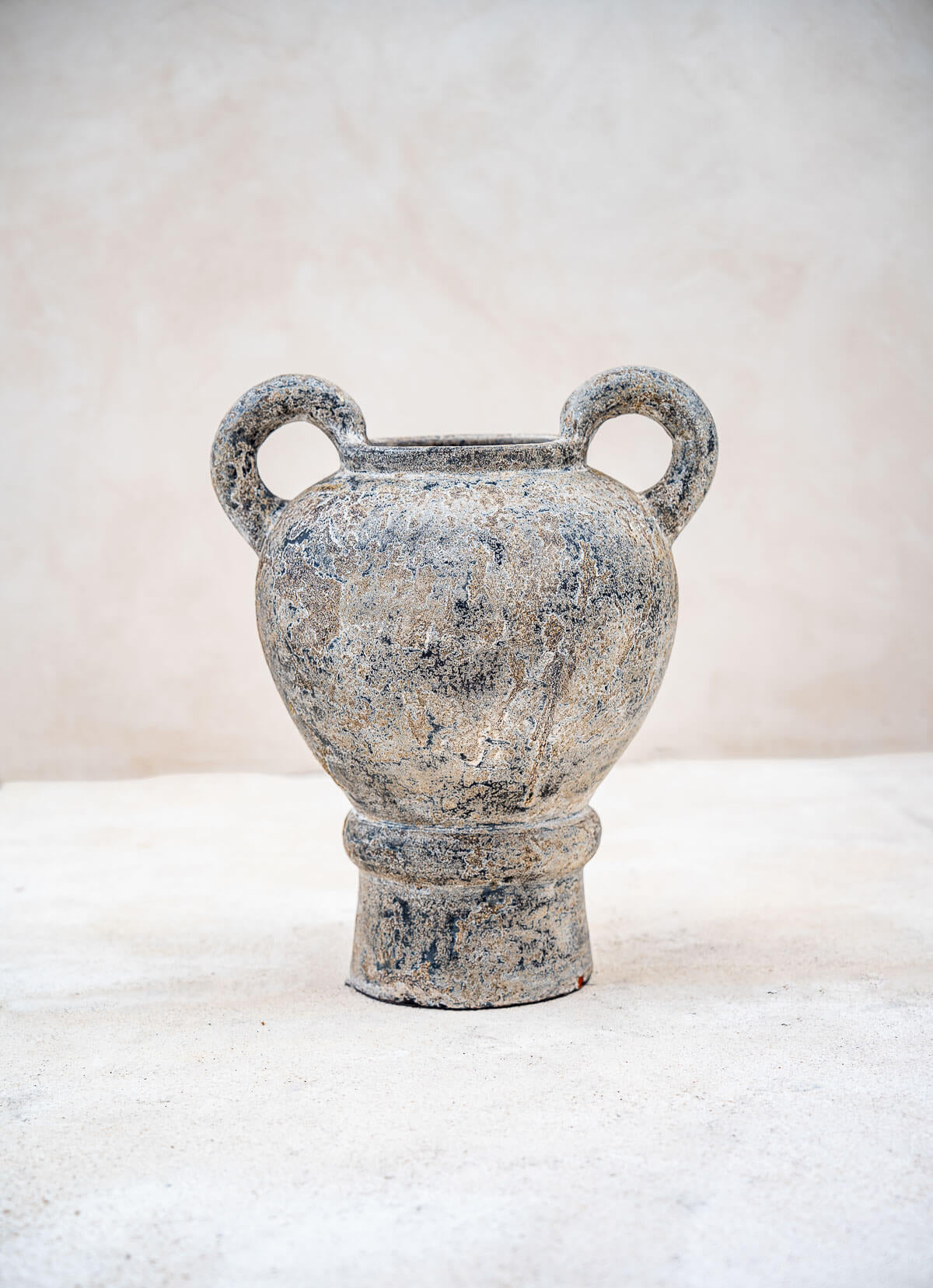 Decorative stone urn with two handles on a white background