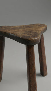 Wooden stool with a curved seat on a plain background