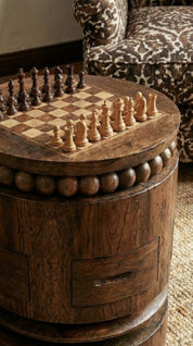 Wooden barrel-shaped table with a chess set on top, next to a patterned chair.