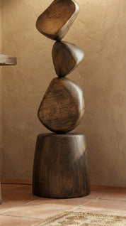 Wooden sculpture of stacked stones on a beige background