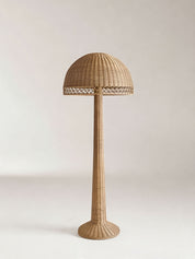 Wicker floor lamp with a dome-shaped shade on a light background